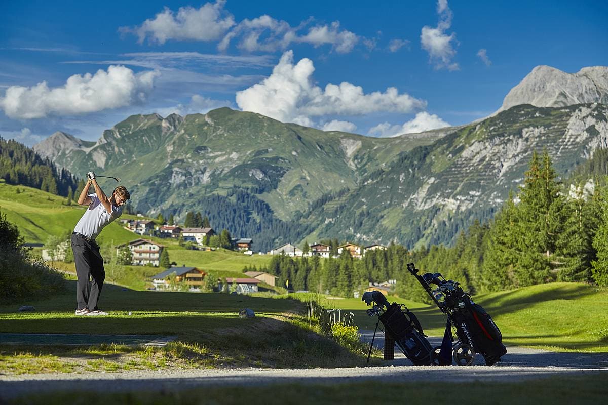 Ein Mann beim Golf-Abschlag auf dem Golfplatz mit den Ausblicken auf Lech und die Berge.